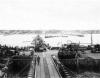 Veículos militares (como M3 Halftracks, um M8 Greyhound e AFKWX Trucks) aproximam-se da costa no porto artificial de Mulberry, através de uma ponte flutuante, para Omaha Beach.
