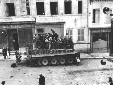 Civis na rua são montados sobre um tanque Tiger I neutralizado.