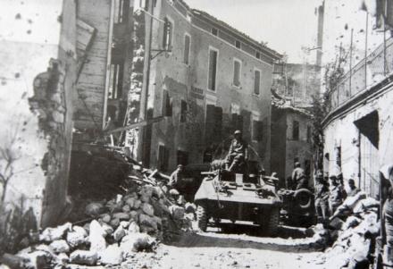 Um blindado M-8 do Esquadrão de Reconhecimento da 1ª Divisão de Infantaria Expedicionária entra em Montese, na Itália, no começo da ofensiva da primavera lançada pelos Aliados.