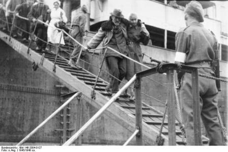 Refugiados a chegarem a porto a Oeste, já ocupado por tropas britânicas.