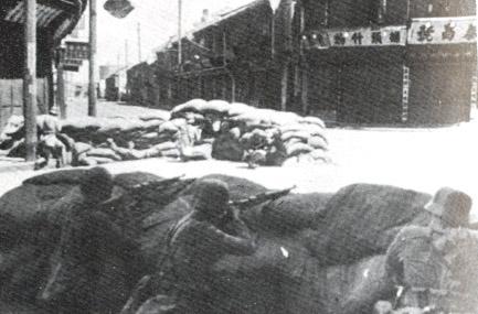 Soldados da 88ª Divisão defendendo um cruzamento atrás de fortificação de sacos de areia.